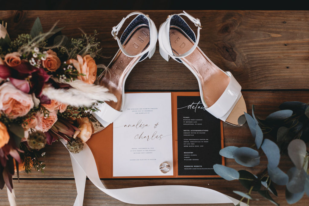 shoes and invites and floral on wood during a mustard seed wedding