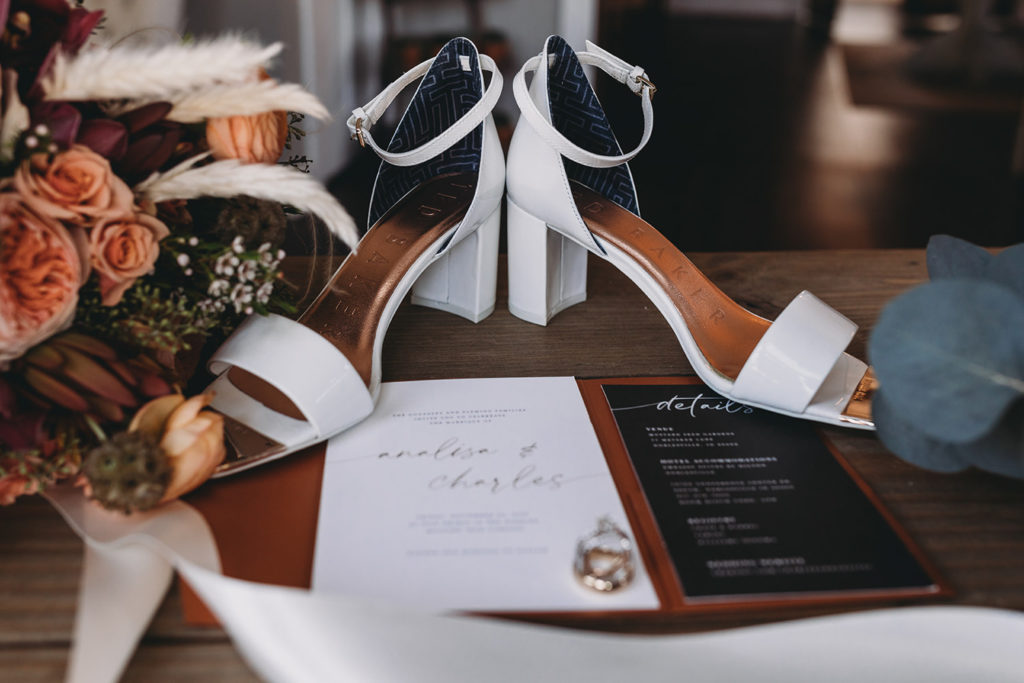 shoes and rings and floral and paper on a wooden surface during a mustard seed wedding