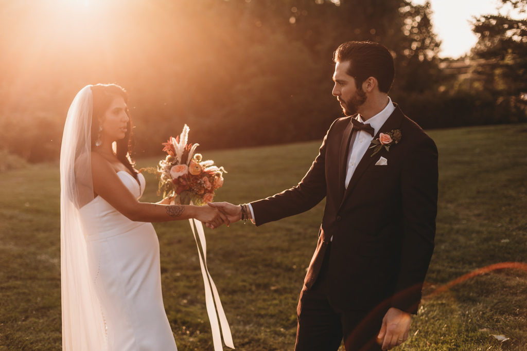 bride and groom hold hands and look at each other with intense passion at sunset during their mustard seed wedding