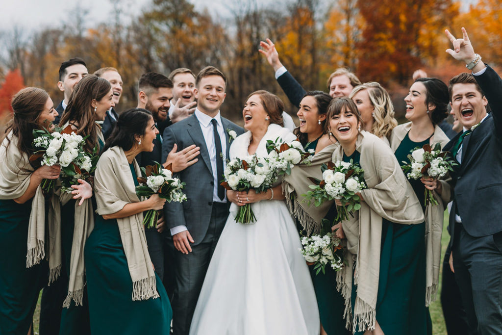 wedding party cheers on bride and groom on cold fall day during their charming carmel wedding