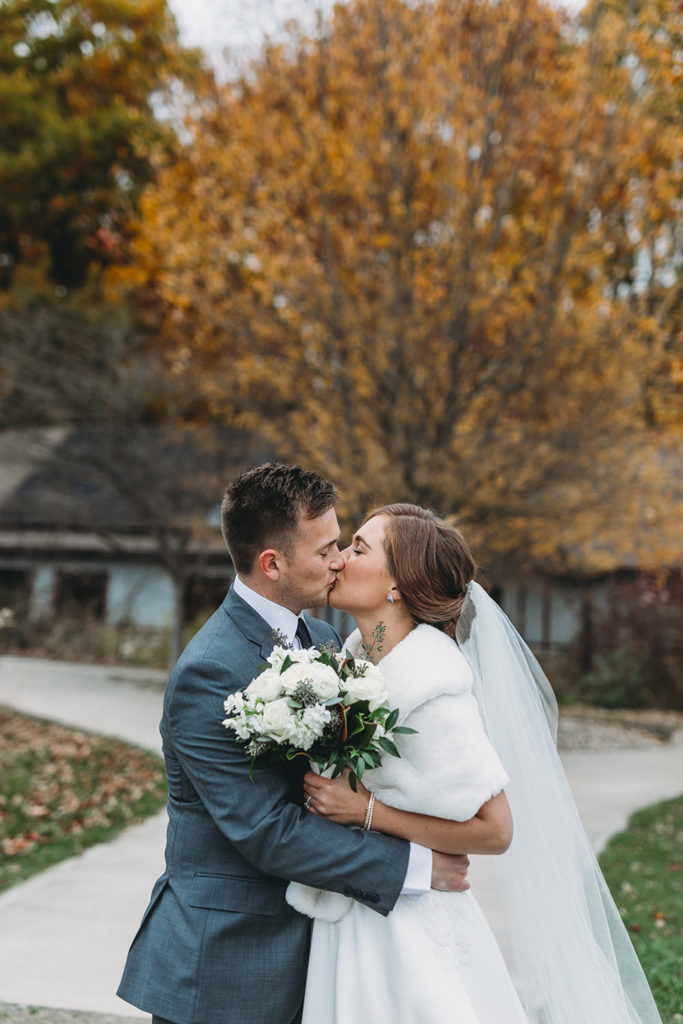 bride and groom kiss in front of tree with yellow leaves during their charming carmel wedding