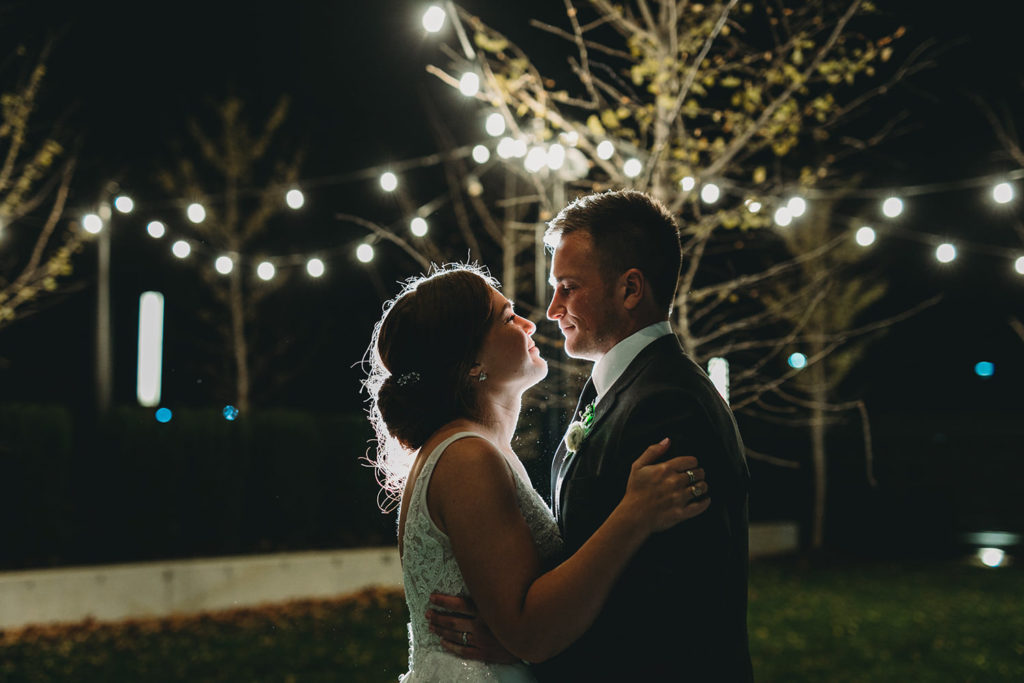 string lights backlight bride and groom at night during their charming carmel wedding