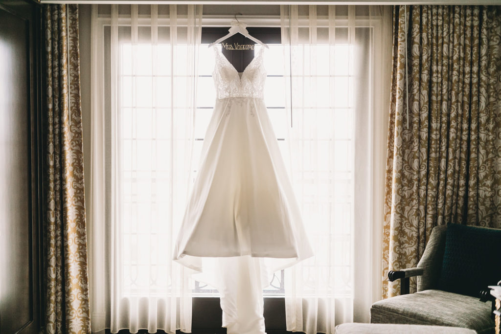 wedding dress hanging in a window during their charming carmel wedding