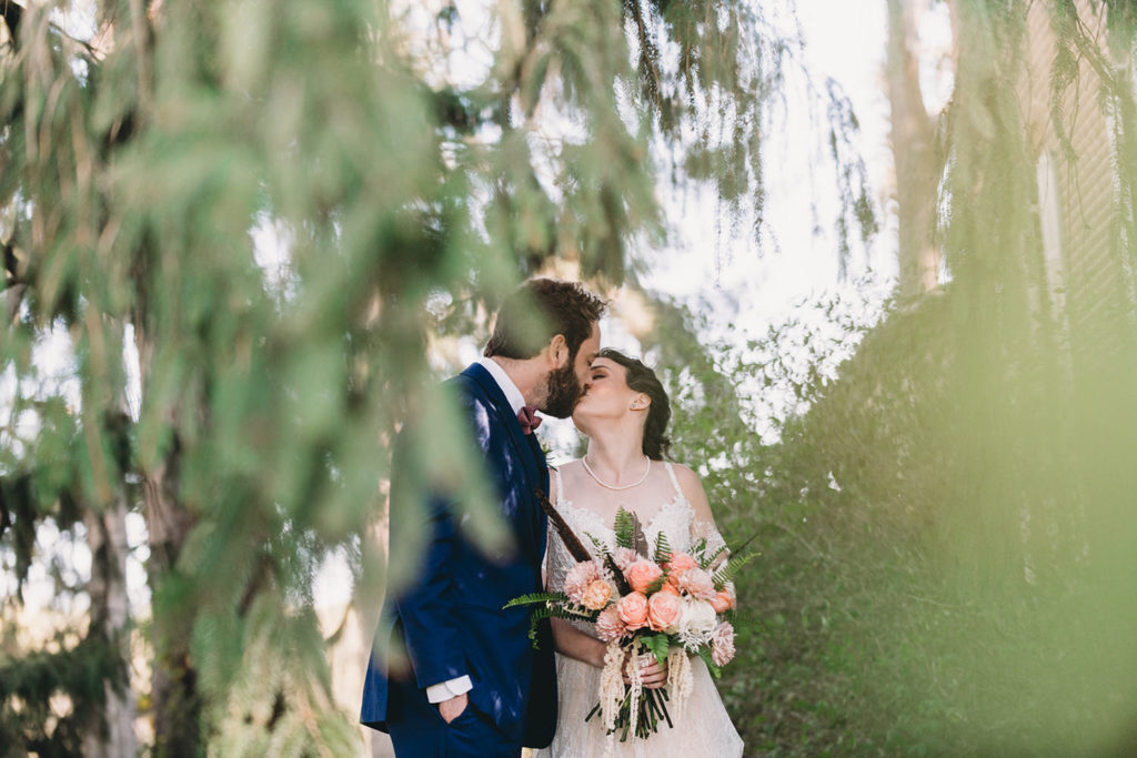 bride and groom kiss whilst framed by leaves of tree during their charming Lindley Farmstead wedding