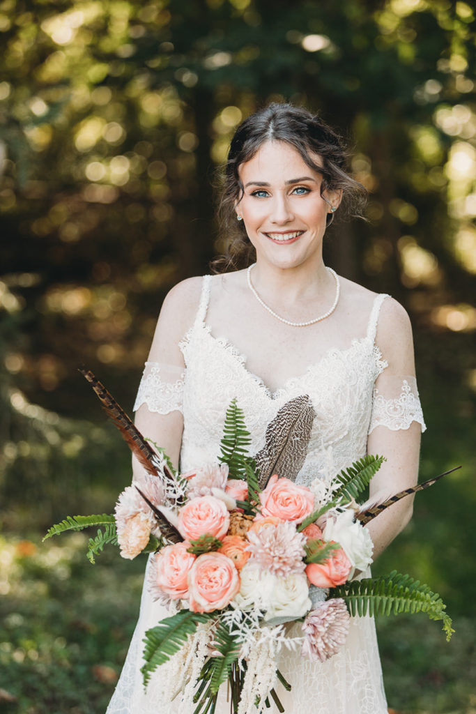 gorgeous bride wearing pearls and holding flowers during their charming Lindley Farmstead wedding