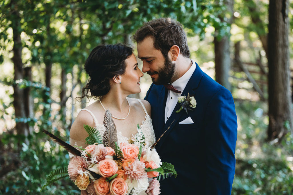 bride and groom touch noses in the forest during their charming Lindley Farmstead wedding
