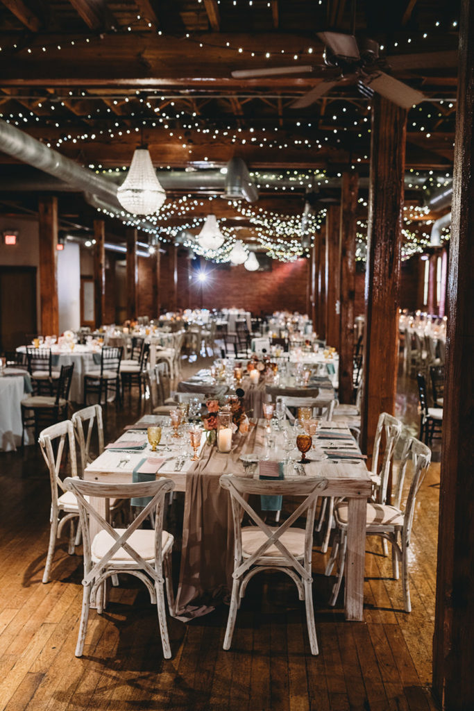 flash backlights wedding event space with string lights above, tables below, autumn colors and flowers, during their mavris reception