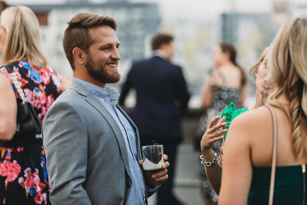 man in suit with dress shirt that is unbuttoned laughs during their mavris reception