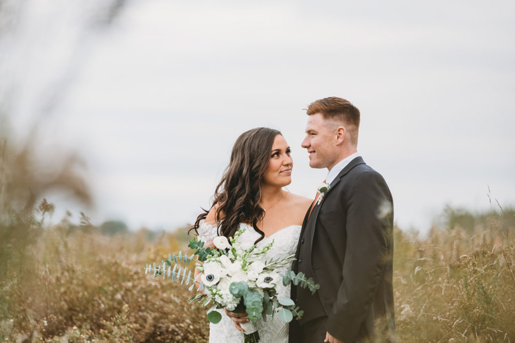 bride gives groom a hard, but loving, look in a field during their white willow farms wedding