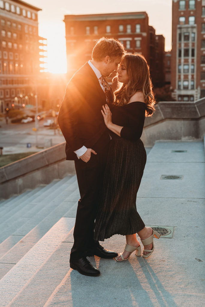 Two people in love, one in a suit and the other in a dress, hold their bodies close together and press their foreheads together while the sun shines over their shoulders. multitalented wedding photographers touching foreheads