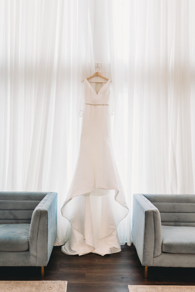 Wedding dress hanging in the window between two gray sofas, symetrical.