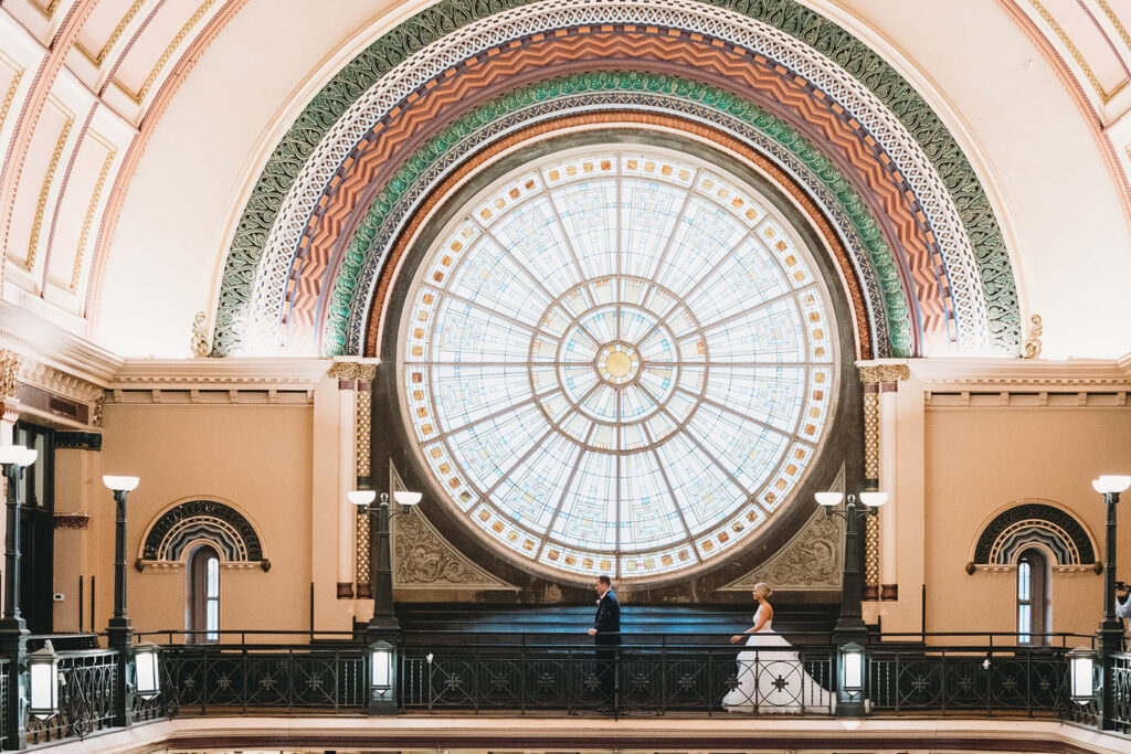 bride and groom first look under stained glass window on blacony for a Union Station Indy Wedding