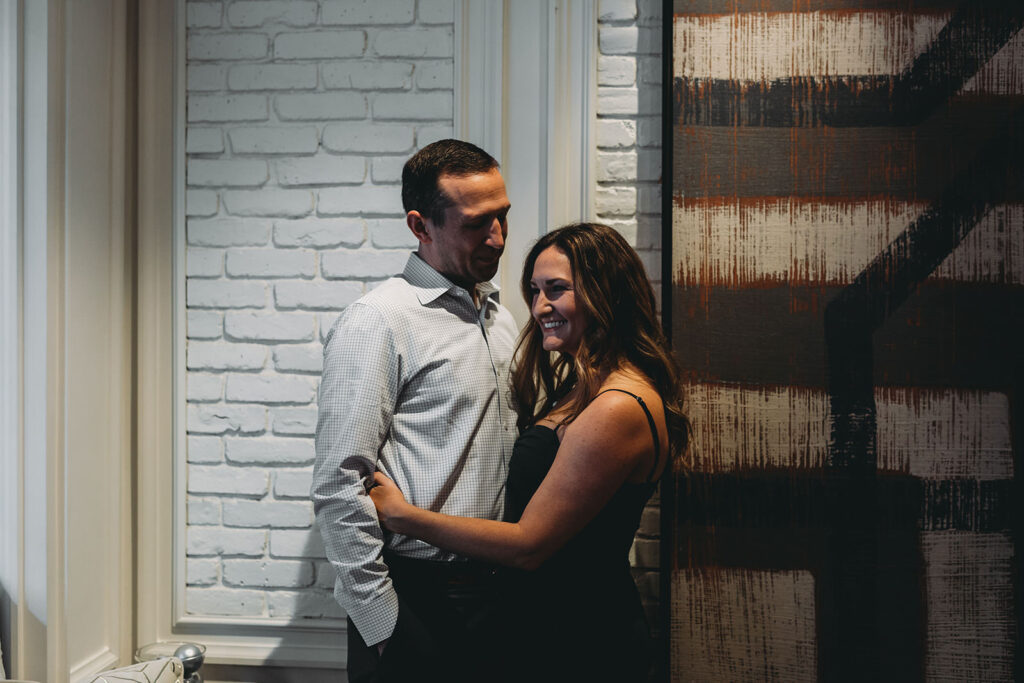 woman hugs man in front of artwork during their le meridien engagement photo session